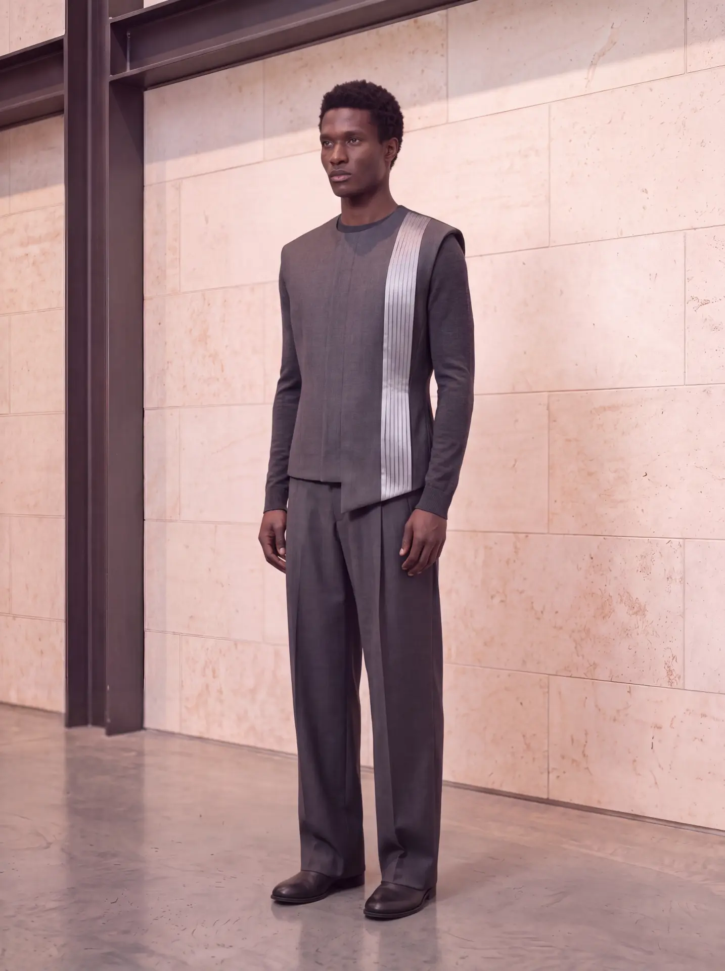 Graphite layered vest with a vertical silver pleated stripe, worn with wide graphite trousers