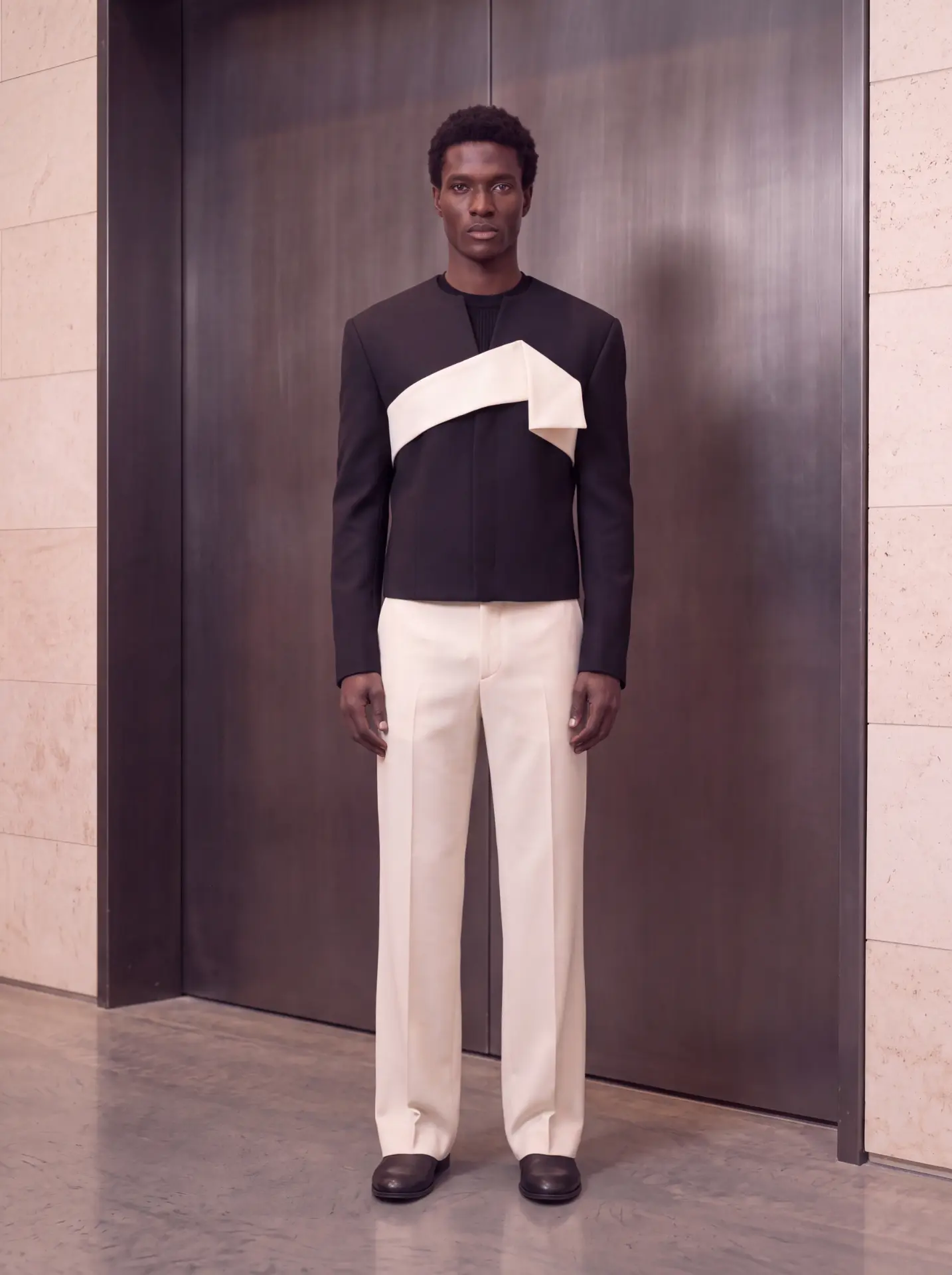 Black cropped jacket with a folded ivory chest detail, worn with ivory trousers